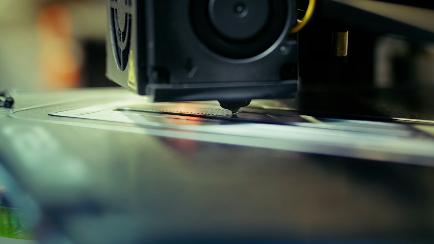 Dysza drukarki 3D wytłaczająca plastik na płytę roboczą.