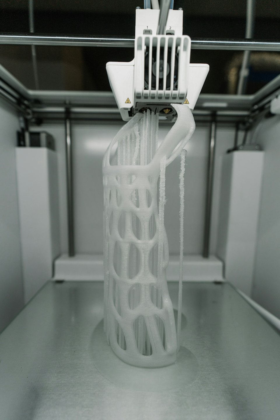 Drukarka 3D tworzy szczegółowy biały obiekt kratownicowy.
